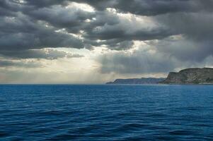 View from the sea to the West Cape in Norway in sunshine with heavy clouds. photo