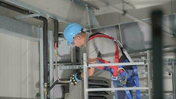 Masculin technicien permanent sur échafaud inspecter contraction et ajustement isolé tuyau Connexions de air circulation système. video