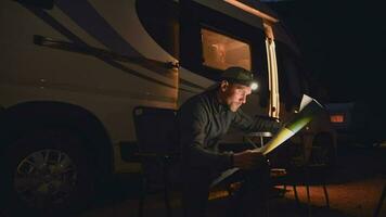 Caucasian Men with Flashlight Reading Local Trials Map in Front of His Motorhome While Camping video