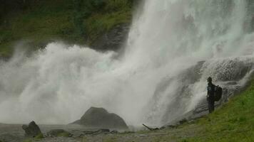 caminhante desfrutando a cênico cascata vista. Noruega, Europa. lento movimento cenas video