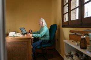 General shot of an elderly man sitting at his desk performing a quantum medicine analysis. photo