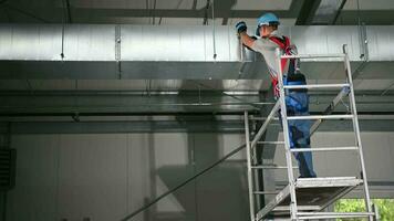 kaukasisch männlich hvac Auftragnehmer Befestigung Metall Klemmen auf Luft Konditionierung Welle gebaut auf Decke. video