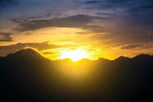 montaña silueta en contra vistoso cielo con puesta de sol foto