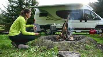 femme en train de préparer nourriture sur feu de camp tandis que dépenses temps seul video