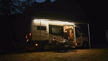 laat avond online afgelegen werk in voorkant van modern camper busje terwijl Aan camping video