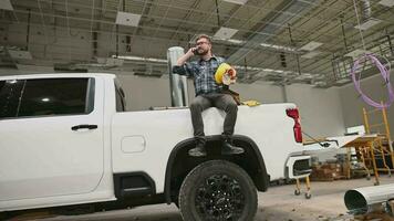 entreprenör arbetstagare talande på hans telefon medan sittplatser på plocka upp lastbil säng video