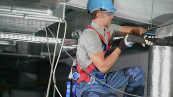 Crouching Male HVAC Expert Fixing Black Insulation On Pipes Of Air Conditioning System. video