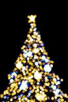 blurred lights illuminating the Christmas tree on a black background photo