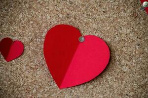 colorful cut out paper hearts on a brown cork background, photo