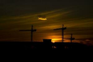 picturesque sunset with clouds in the sky in the city with construction cranes, photo