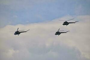 flying combat helicopters against a blue sky with clouds on a sunny day photo