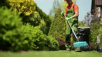 ouvrier ratissage herbe champ dans une jardin. caucasien jardinier dans le sien 30s. video