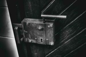 old antique lock with a handle in a wooden door close-up in the building photo
