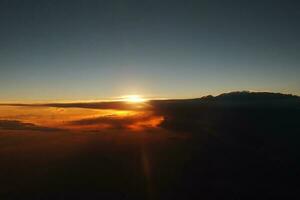misterioso puesta de sol con nubes desde el avión ventana con foto