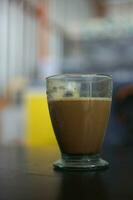 cappuccino served in small size clear glass coffee cup over blurred background selective focus. photo