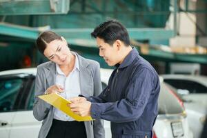 Auto mechanic and female manager in auto repair shop, Mechanic and young woman client talking together at the repair garage, Car repair and maintenance concepts photo