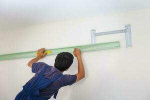 Young repairman fixing air conditioner unit, Asian technician man installing an air conditioning in a client house, Maintenance and repairing concepts photo