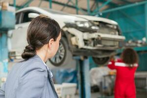 Female manager and auto mechanic in auto repair shop, Mechanic and young woman client talking together at the repair garage, Car repair and maintenance concepts photo