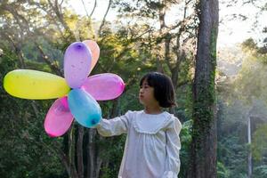 Portrait of child girl playing with colorful toy balloons in the park outdoors. photo
