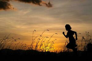 silueta de niña corriendo en el prado al fondo del atardecer. foto