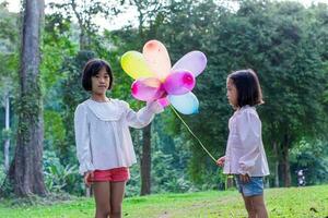 dos niño niña participación vistoso juguete globos en el parque al aire libre. foto