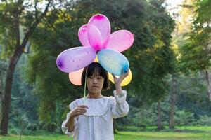 Portrait of child girl holding colorful toy balloons in the park outdoors. photo