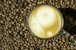 Crema of black coffee in a clear glass on a coffee beans background, selective focus, soft focus. photo