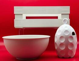 Bologna  Italy  May 23, 2023 A white set of kitchen utensils isolated on red background. Design object made in Italy by Guizzini with recycled material. photo