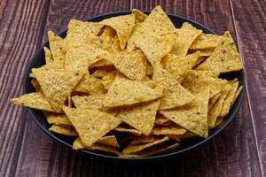 nachos en un negro bol. tortilla papas fritas en de madera antecedentes. foto