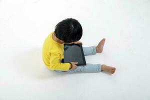 South East Asian young boy child playing tablet tab computer pc on white background photo