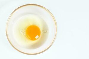 Raw Egg Yolk and white liquid in transparent glass bowl white background photo