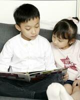 Brother sister chile sit on sofa reading writing study teaching photo