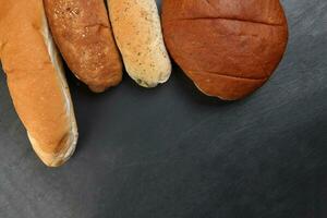 Freshly baked bread loaf bun roll round long mix verity copy text space border frame black background photo