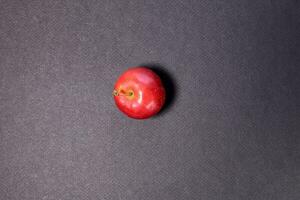 Small mini red apple on black background photo