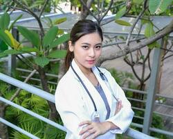 South East Asian young Malay Chinese woman medical doctor stethoscope stand pose outdoor photo