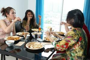 Young southeast asian woman group talk celebrate eating enjoying food rice curry noodle chicken drink cheers on dining table photo