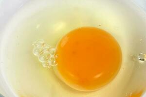 Raw Egg Yolk and white liquid in transparent glass bowl white background photo