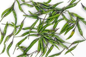 Fresh birds eye green chilli scattered top view on white background photo