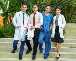 South East Asian young Malay Chinese man woman medical doctor stethoscope apron group stand pose confident look forward photo