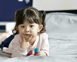 uno niña niños acostado en cama mirando adelante posando foto