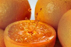 Orange real juice splash over fresh half cut fruit photo