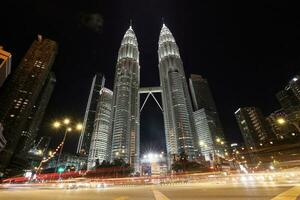 kuala lumpur, malasia-febrero 12, 2020 calle nivel ver de el petronas gemelo torres un turista atracción y un comercial centro. con coche ligero caminos foto