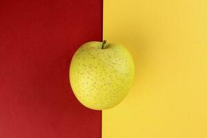 yellow green apple on yellow red colour paper background copy space for text photo