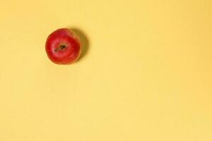 Small mini red apple on yellow background photo