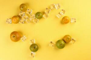 small yellow green mandarin ice cube orange on yellow colour paper background copy space for text photo