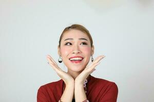 Asian woman traditional red maroon kebaya sharong on white background happy smile surprised hand on cheek photo