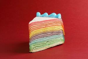 Rainbow crepe layer cake on red background photo