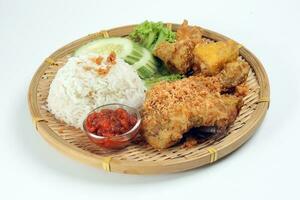 Ayam penyet a East Javanese cuisine smashed fried chicken dish with floss sambal slices of cucumbers fried tofu and tempeh photo