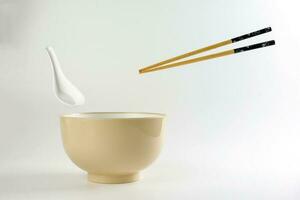 Empty oriental Japanese Chinese soup bowl spoon chopstick elevated flying in air off white photo