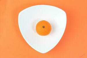 Mandarin Orange Fruit slice half juiced extracted on hart shape plate orange background photo